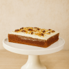 Classic carrot cake topped with smooth cream cheese frosting and walnut pieces